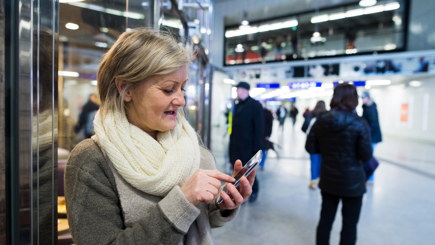 woman on smartphone using solo travel safety app in airport